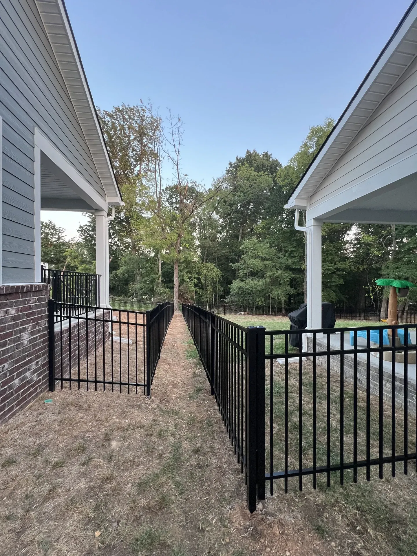 Black aluminum gates and parallel fence lines between two homes