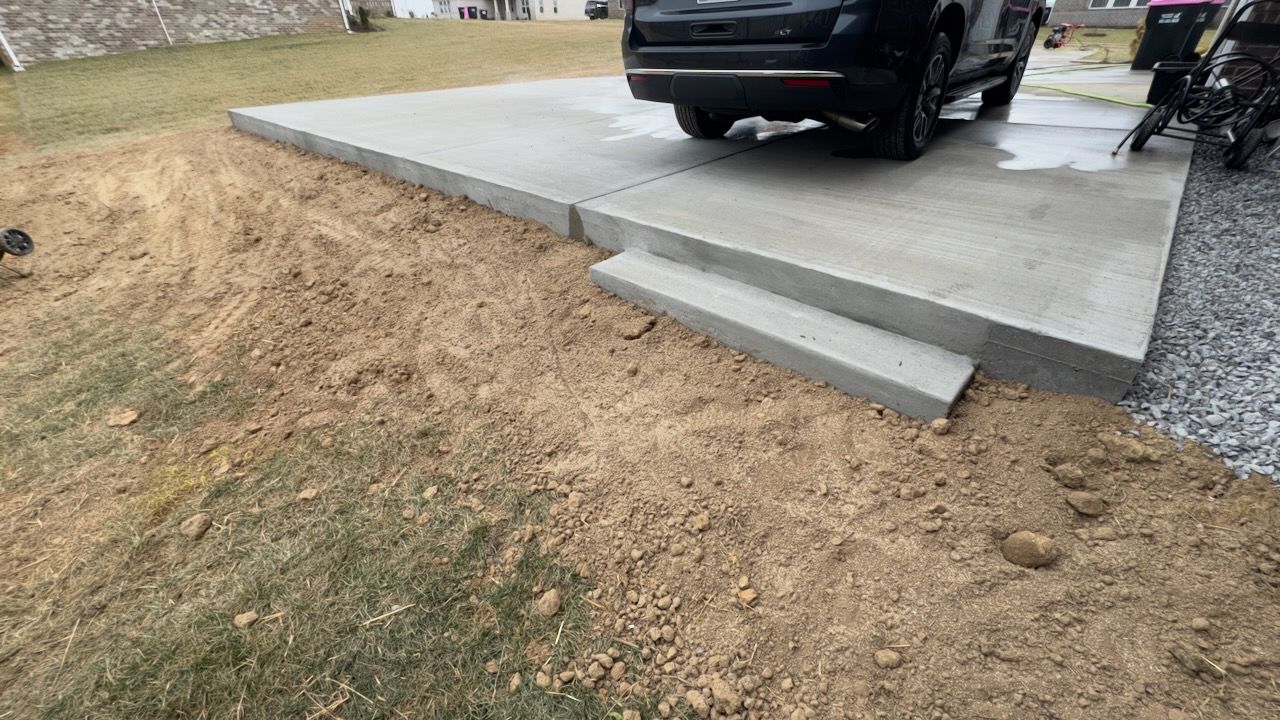 Concrete driveway extension providing additional parking space for vehicles or RVs.