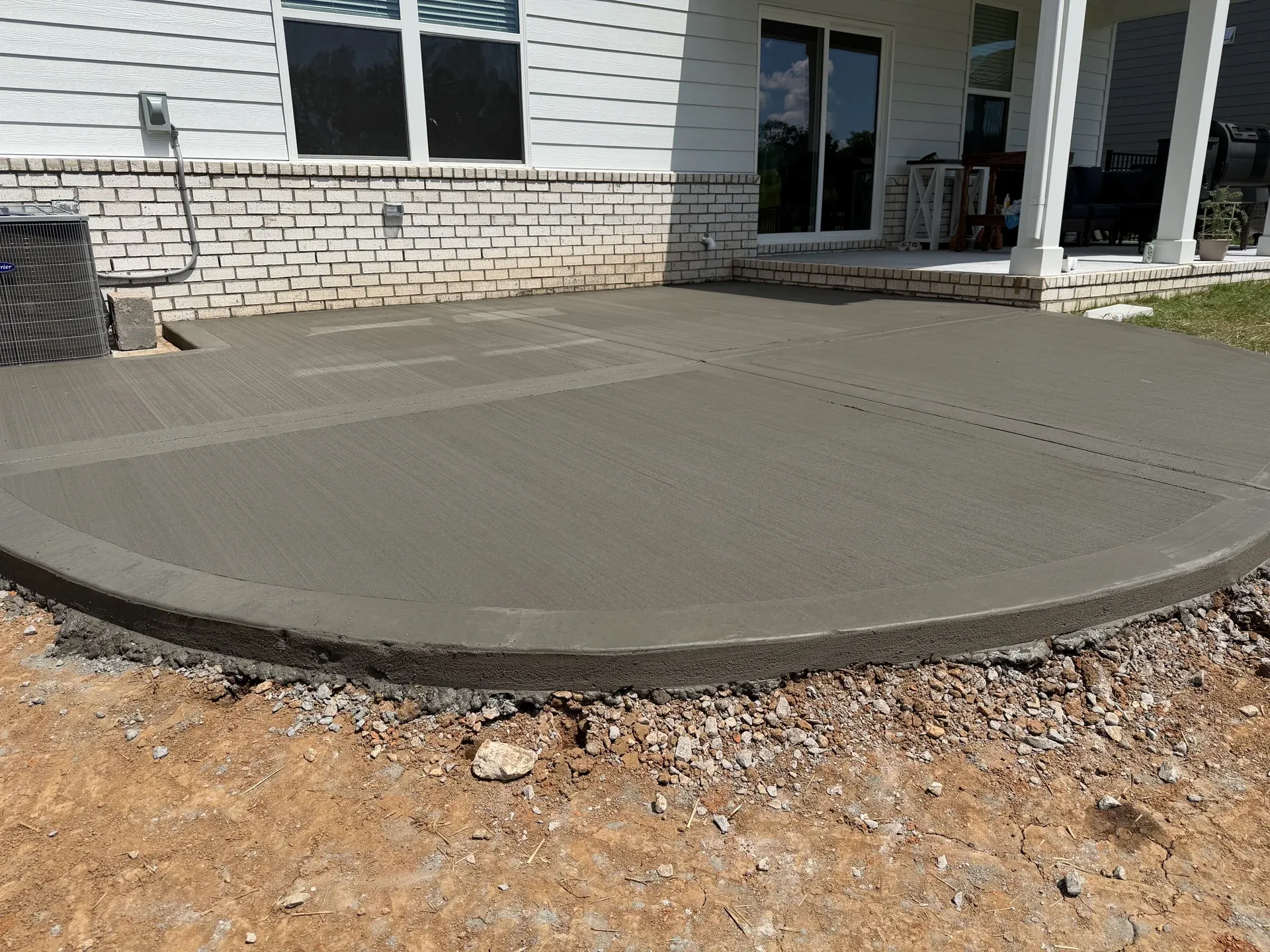 Concrete patio with a rounded outer edge beside a covered porch