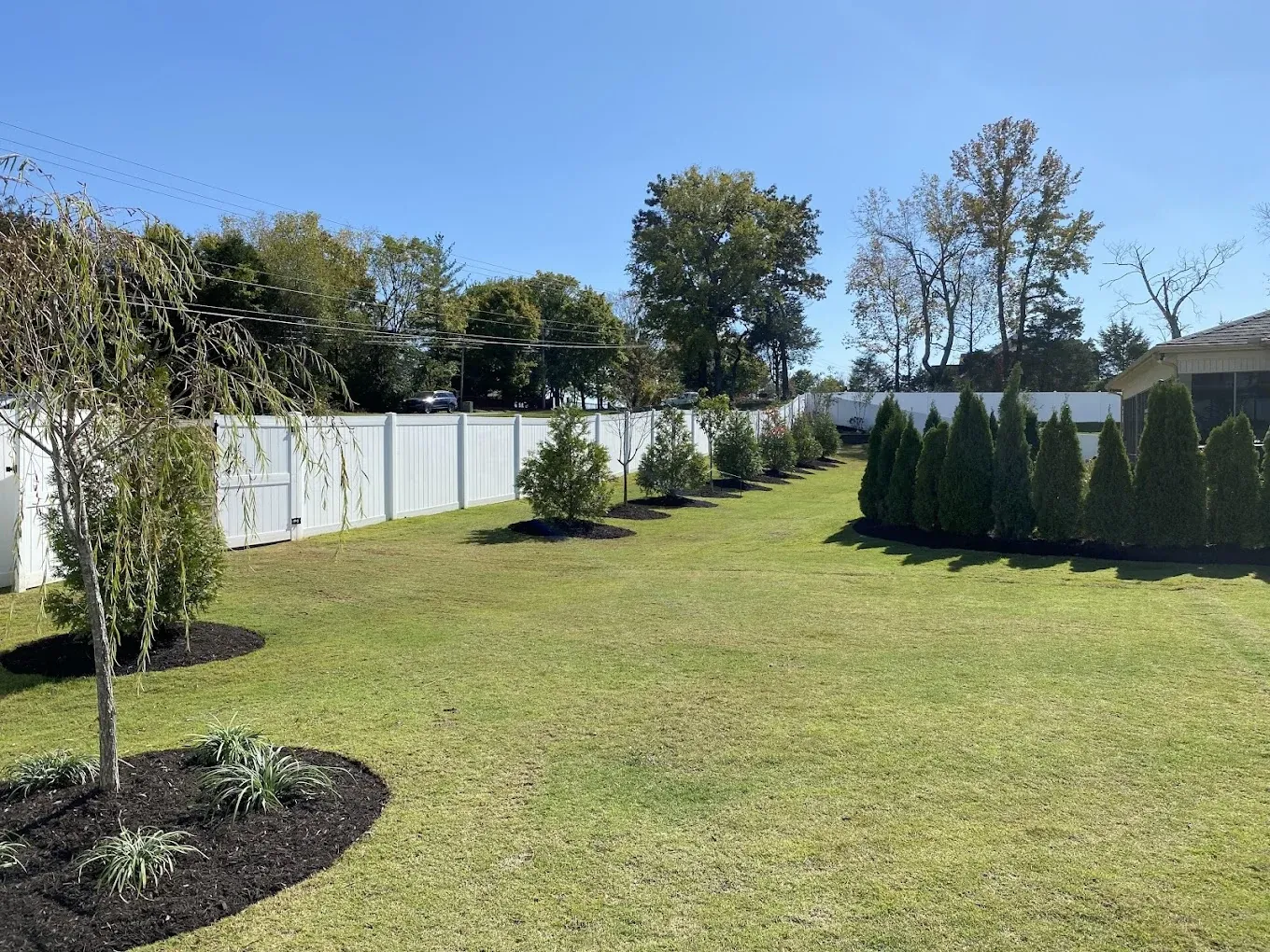White vinyl privacy fence bordering a landscaped lawn