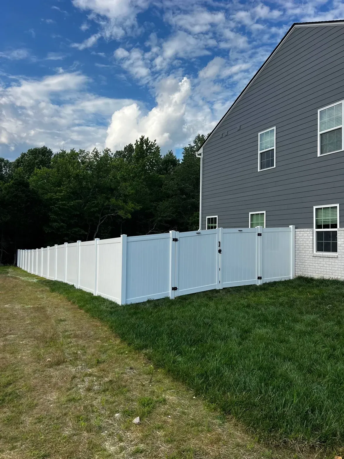 White vinyl double gate beside a gray house