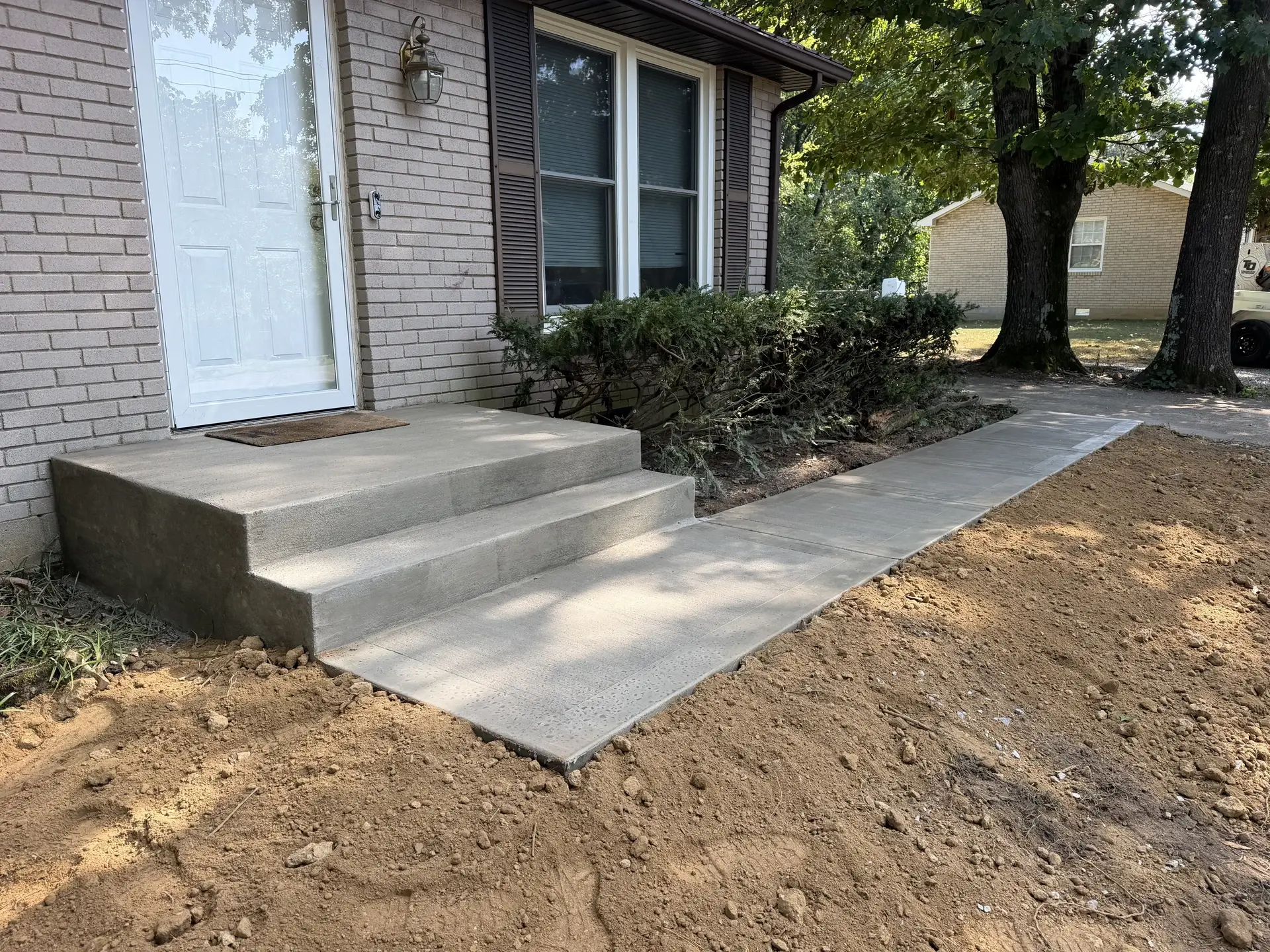 Concrete front-entry steps and walkway beside a brick home