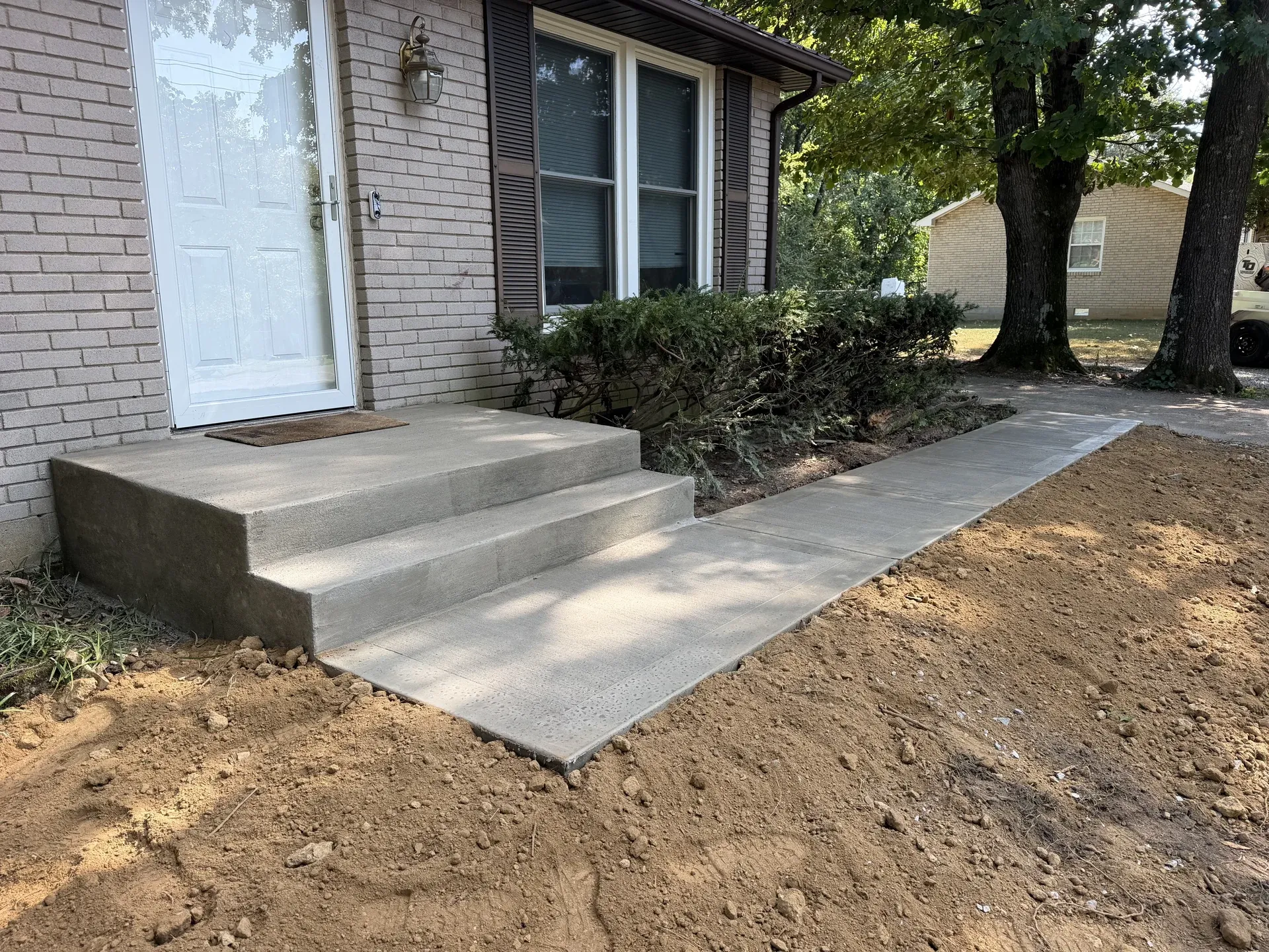 Concrete front-entry steps and walkway beside a brick home