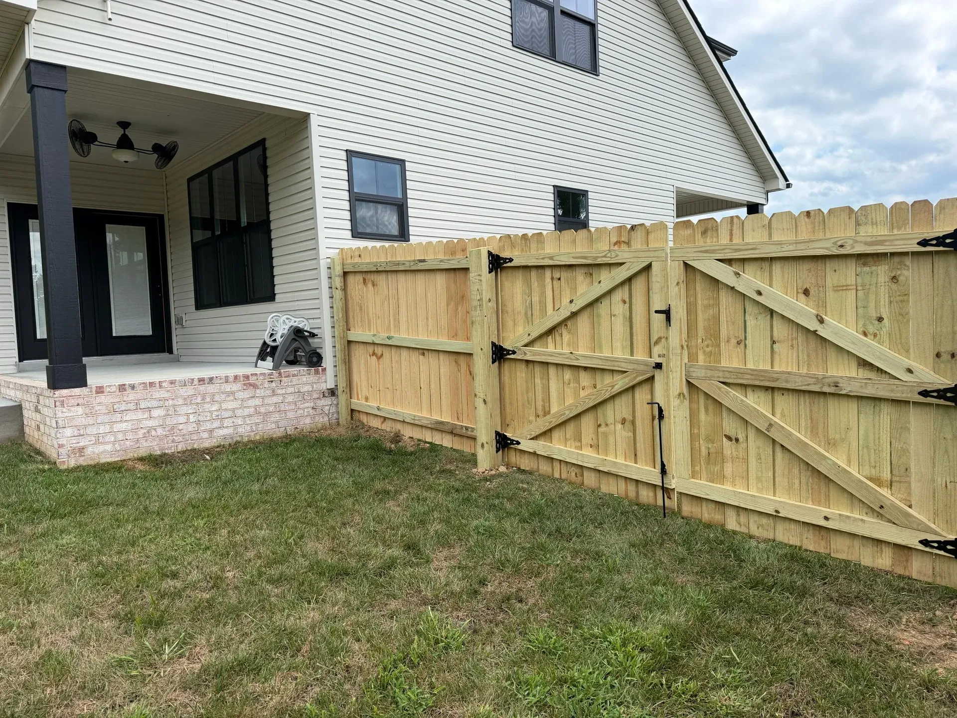 Inside view of a wood double gate showing diagonal bracing and black hinges