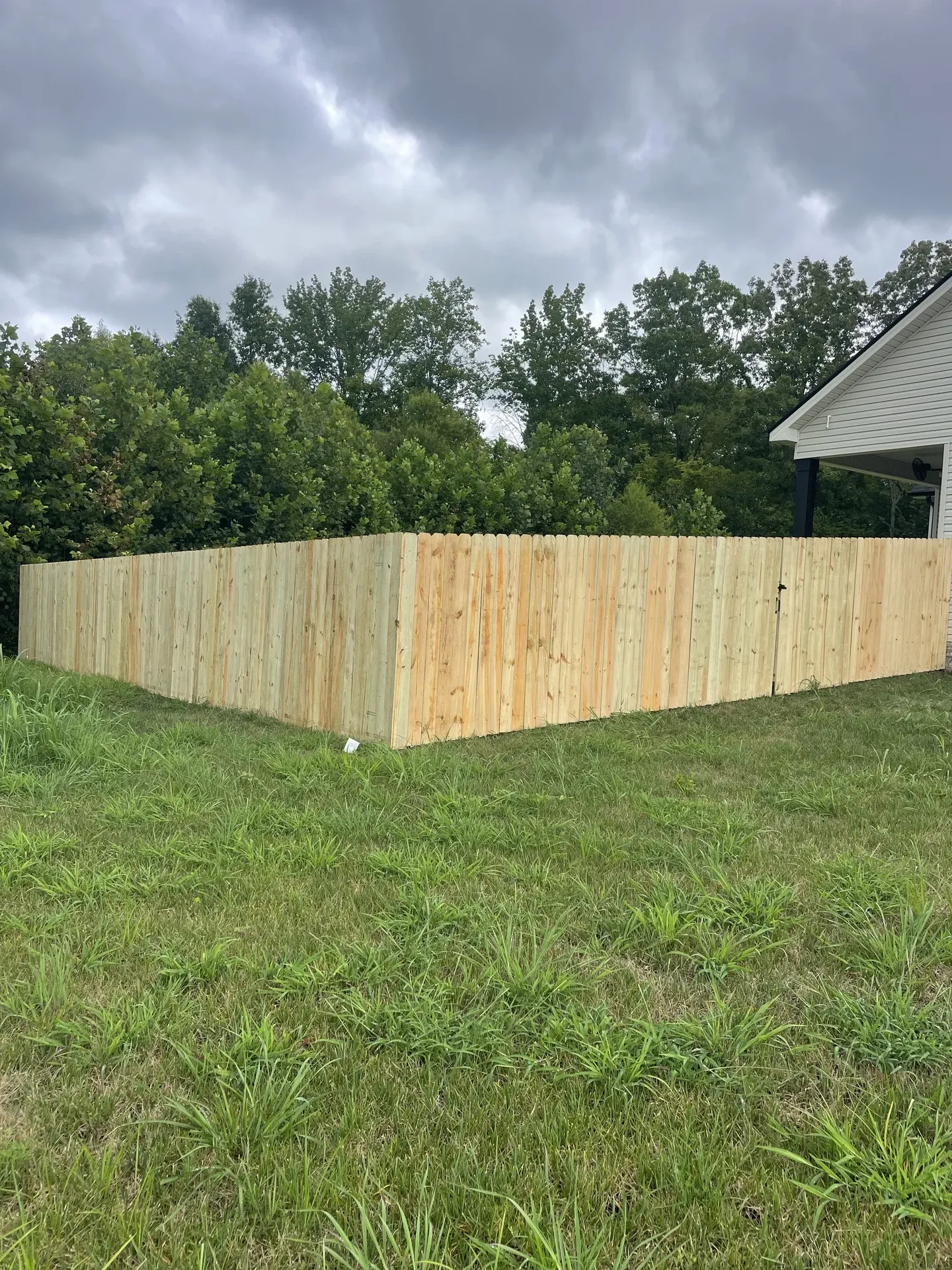 Wood privacy fence corner beside a covered porch
